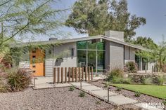 a modern house with an orange door in the front yard