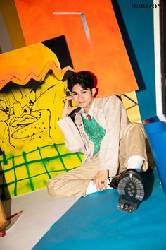 a young man sitting on top of a bed next to a wall with graffiti painted on it