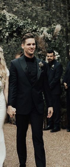 a bride and groom holding hands in front of their wedding party at the end of an outdoor ceremony