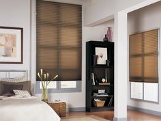 a bed room with a neatly made bed and two windows covered in shades that are brown