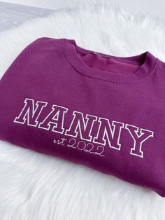 Personalised sweatshirt embroidered with Nana in coordinating thread & est year. Children's names or initials can be added to the sleeve with a heart. Add up to 3 names. NANA can be changed to NANNA,NANNY, GRANDMA . Please put this in the personalisation box. Material: 80% combed cotton/ 20% polyester We recommend approx sizing: XS 6-8 S 8-10 M 10-12 L 12-14 XL 14-16 XXL 16-18 3-5XL can be provided in certain colours please message us to discuss. 💜 WHY SHOP WITH US 💜 We lovingly embroider cute Embroidered Jumper, Baby Skin, Embroidered Sweatshirts, Nanny, Kid Names, Cricut Projects, A Heart, Combed Cotton, Initials