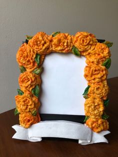 an orange flowered photo frame is on a table with a white ribbon around it