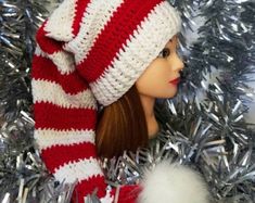 a doll wearing a red and white striped hat next to a silver tinsel christmas tree