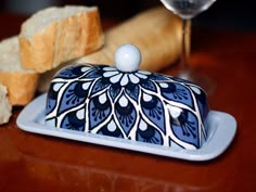 a blue and white dish sitting on top of a wooden table next to some bread