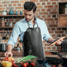 a man in an apron chopping vegetables on a cutting board