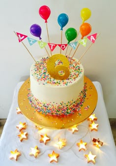 a birthday cake with candles and stars around it on a white tablecloth covered table