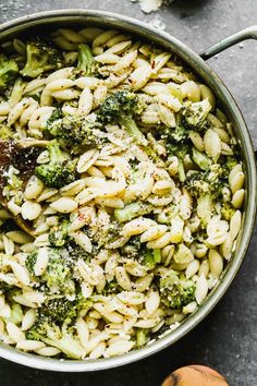 a pot filled with pasta and broccoli on top of a table