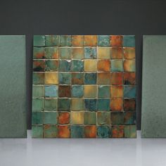 three green and orange tiles on the wall next to each other in an empty room