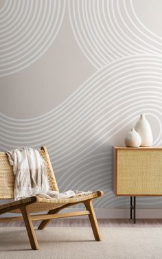 a wooden chair sitting next to a white vase on top of a table in front of a wall