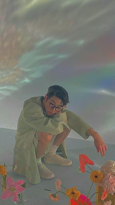 a painting of a man kneeling down in front of some flowers and sky with clouds