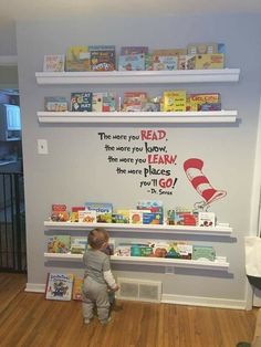 a little boy that is standing in front of a shelf with some books on it