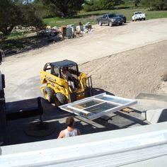 a forklift driving down a dirt road next to a loading dock with people on it