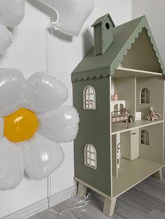 a doll house next to balloons in the shape of flowers