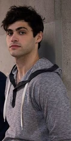 a young man leaning up against a wall