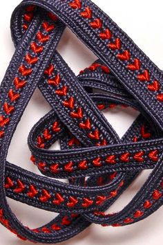 a close up of a rope on a white surface with red and black braiding