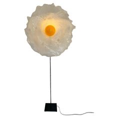 an egg on a black stand with a white light shining in the center, and a wire running through it