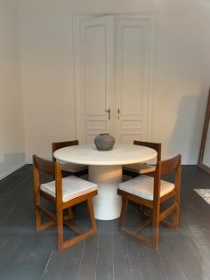 a white table with four chairs and a bowl on it in a room that has hardwood floors