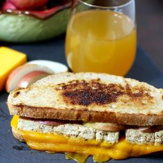 a grilled cheese and tomato sandwich next to a glass of orange juice