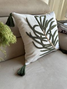 a white couch with a green leaf pillow on it's back and two books in the background