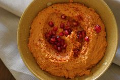 a bowl filled with hummus and pomegranates on top of a table