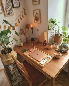 a wooden desk topped with a laptop computer sitting on top of a wooden table next to a potted plant