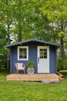 a small blue shed sitting on top of a lush green field