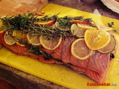 raw salmon with lemons and herbs on a yellow cutting board