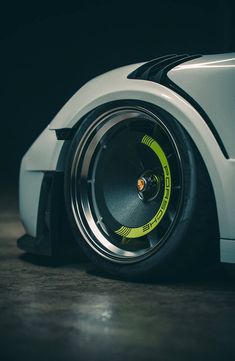 the front wheel of a white sports car with yellow stripes on it's tires