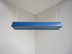 a blue light hanging from the ceiling in a room with white walls and flooring