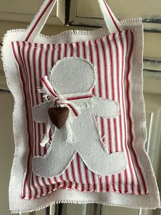 a red and white striped pillow hanging from a hook on a door handle with a heart in the middle