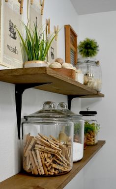 two shelves with jars and wooden dows on them, one shelf has plants in it