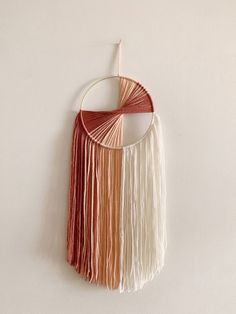 a wall hanging with fringes on it and a circular object in the middle that says,