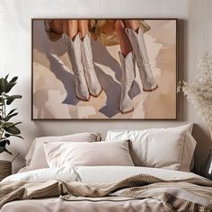 a painting hanging above a bed with pillows and blankets on it, next to a potted plant