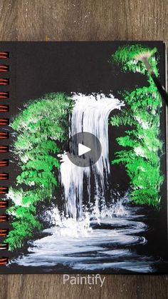 a notebook with a waterfall and trees painted on it