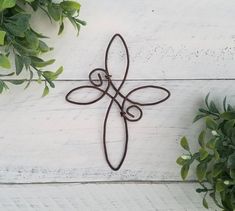 a metal wall hanging on the side of a white building with green leaves around it