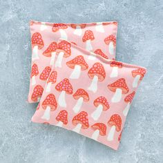 two red and white mushrooms on pink fabric