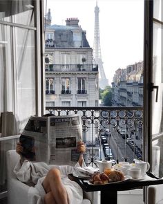 a person sitting in a chair reading a newspaper while holding a tray with food on it