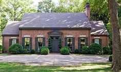 a brick house surrounded by trees and grass