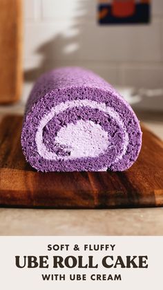 a roll of purple cake sitting on top of a wooden cutting board with the words soft & fluffy ube roll, cake with use cream