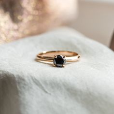 two gold rings sitting on top of a white cloth covered tablecloth with a black diamond in the center