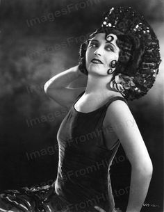 an old black and white photo of a woman in a dress with a hat on her head