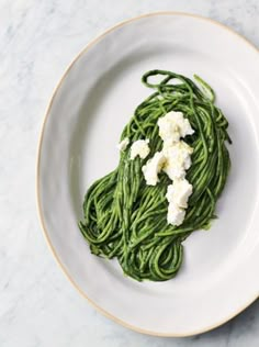 a white plate topped with green pasta covered in fettuccine and cream cheese