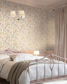 a white bed sitting next to a window with curtains on the windowsill and two lamps hanging above it