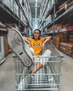 a woman sitting in a shopping cart with her feet on the basket and looking at the camera