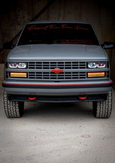 the front end of a gray truck with red lettering on it's grills