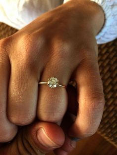 a close up of a person's hand with a diamond ring on their finger