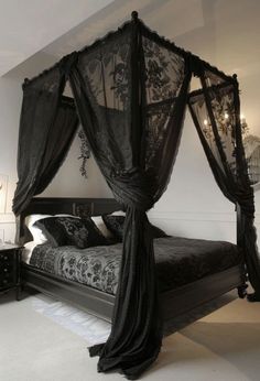 a black canopy bed in a white bedroom