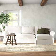 a living room with a white couch and wooden beams on the ceiling, along with a potted plant