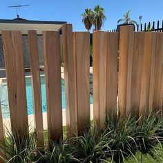 a wooden fence next to a pool in a backyard with grass and plants on the ground