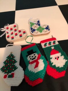 three christmas stockings and two ornaments on a black and white checkered tablecloth,